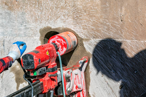 istock Worker is drilling to concrete wall with core drill machine in the construction site. A modern core drill is a drill specifically designed to remove a cylinder of material, much like a hole saw. 1347412884
