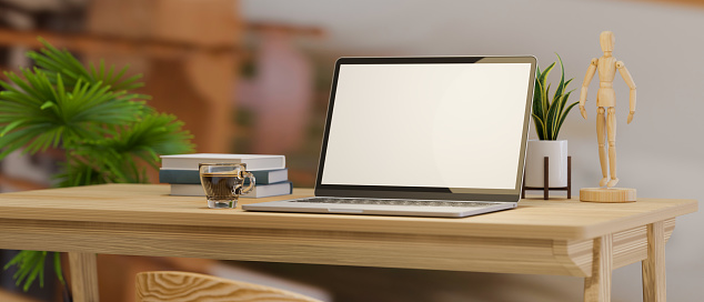 Close-up computer desk with laptop computer blank screen mockup and decor on wooden table over blurred home office background. 3d rendering, 3d illustration