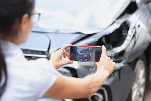 Insurance agent woman takes pictures by smartphone of car damage after road accident Insurance agent woman takes pictures by smartphone of car damage after road accident. Vehicle inspection and damage assessment concept property damage stock pictures, royalty-free photos & images