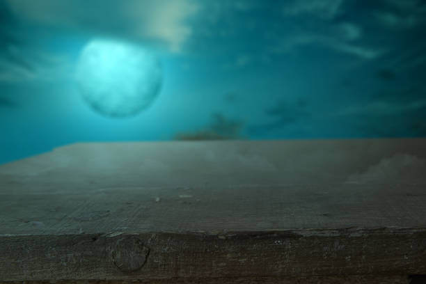 istock Wooden table with a full moon with dark cloudscapes on the night 1347418013