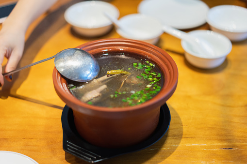 A woman beat duck soup with a spoon,Close up of hand