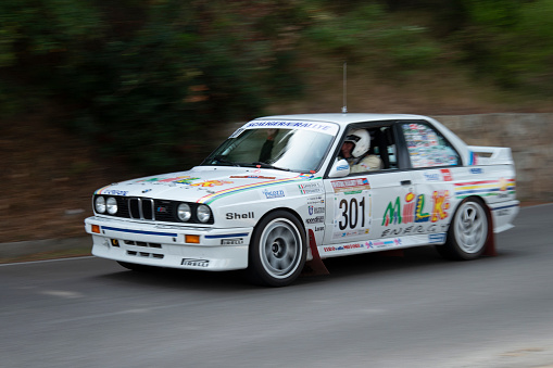 Blue rally car racing on a gravel road, gravel and dust spraying out as it comes round the corner at speed.