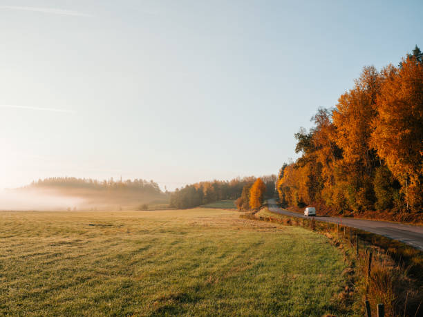 car on road in foggy morning landscape in nature in autumn stock photo