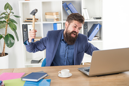 Destroy laptop. Hateful job. Bad computer. Mad manager. Annoyed user. Slow internet connection. Outdated software. Computer lag. Lagging system. Hate office routine. Man bearded crush computer.