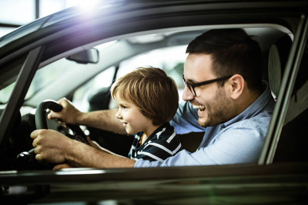 istock Happy father and son testing new car in a showroom. 1347430694