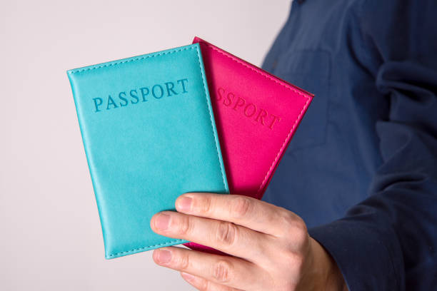 The hand holds two passports with an unknown citizen. The concept of dual citizenship.