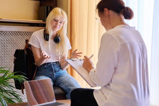 Counselor, social worker, psychologist advising female teenager in office. Conversation of doctor and girl student, mental health of adolescents. Psychology, psychotherapy, discussion, interviews