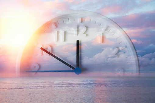 Beautiful lilac sky, ocean and close up of clock. Double exposure. Copy space. Concept of Daylight Savings Time.