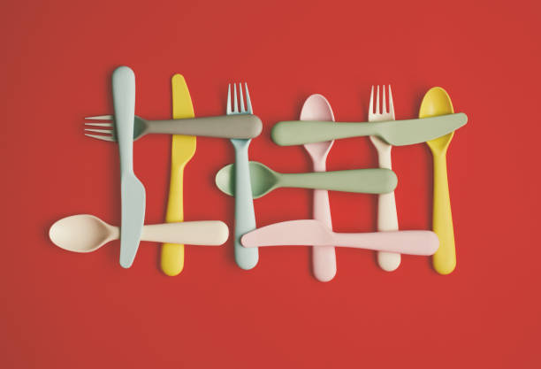 istock Plastic spoons, fork and knifes lay down on pastel red background. Flat lay horizontal composition, creative minimal diet cutlery concept 1347432790