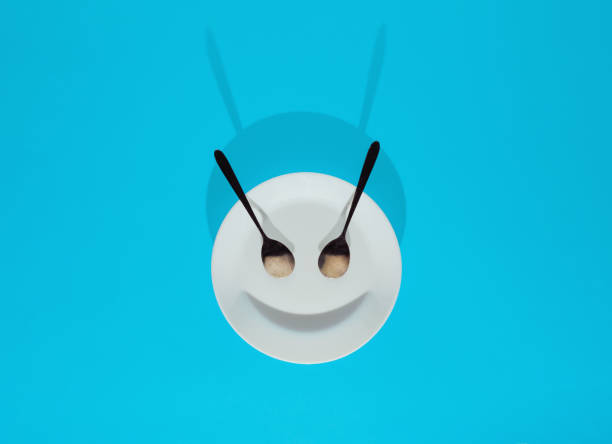 istock Evil face made of ceramic plate, spoons and shadow. Flat lay composition on bright blue bsckground, creative minimal funny diet concept 1347432805