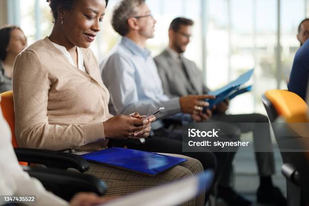 Smiling Black Businesswoman Using Cell Phone On A Seminar Stock Photo - Download Image Now