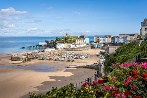 Tenby Harbor, Pembrokeshire, Wales, the United Kingdom. Boats on the beach at low tide. Colorful buildings of popular Welsh resort on a sunny Summer day.