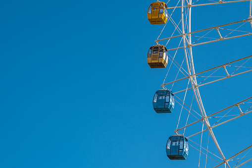 Detail view of a ferris wheel under blue sky.
