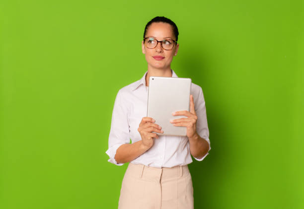 istock Young business woman using tablet isolated over green background. 1347443459