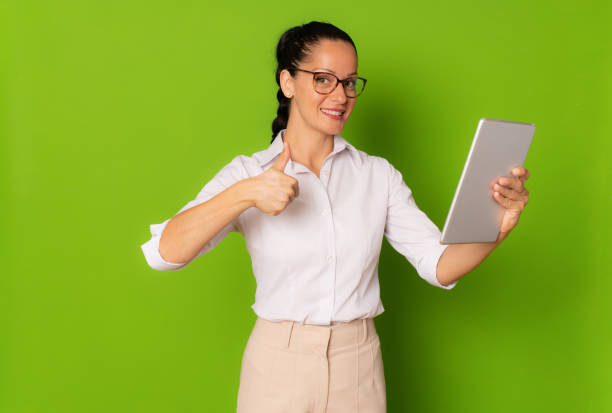 istock Young business woman using tablet isolated over green background. 1347443755