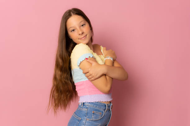 istock cheerful cute girl hugging herself isolated over pink background. 1347449306