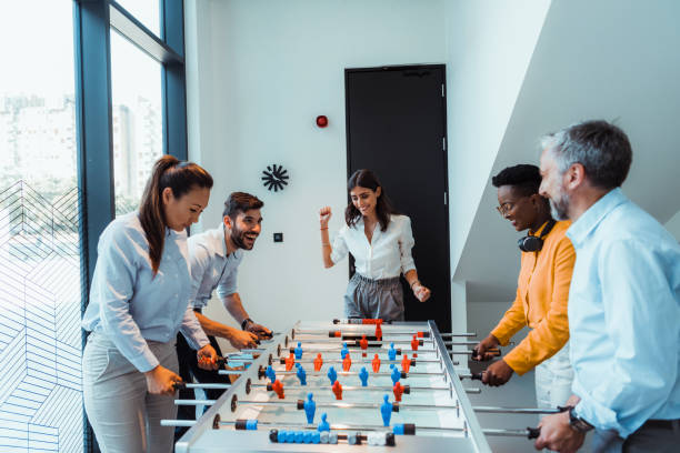 istock Colleagues playing table football in modern office. 1347449334