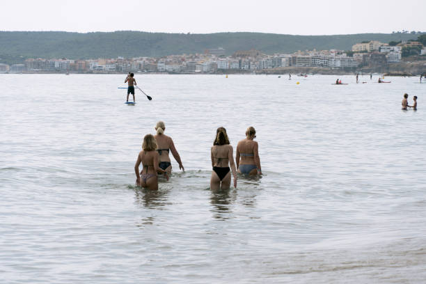 Girona, Spain - August 10, 2021: Mothers and daughters walk through the water on crowded beach
