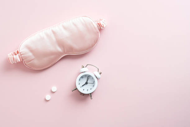 istock Sleeping eye mask, alarm clock, pills on pink background. Insomnia treatment concept. 1347449613