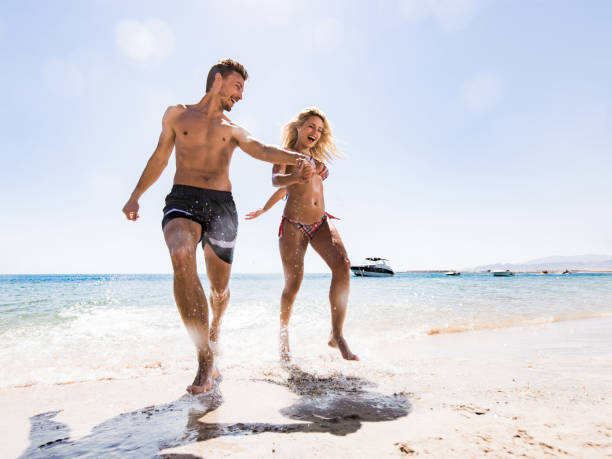 istock Cheerful couple having fun while running through sea in summer day. 1347450317