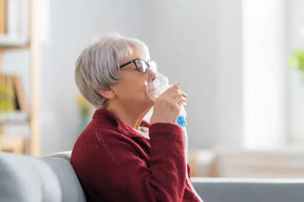 Photo of Elderly woman using inhaler for asthma