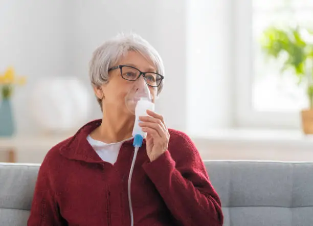 Photo of Elderly woman using inhaler for asthma