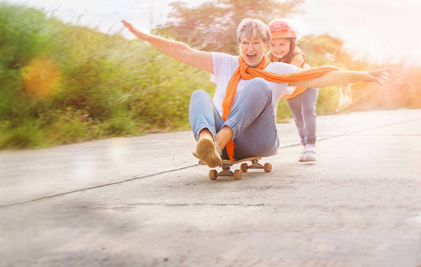 senior e bambino su skateboard - grandmother action senior adult grandparent foto e immagini stock