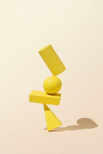 Balance of simple, yellow geometric shapes with shadows on monochrome background