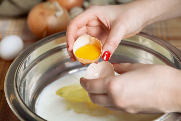 istock Female hands hold halves of egg shell with  yolk 1347459184