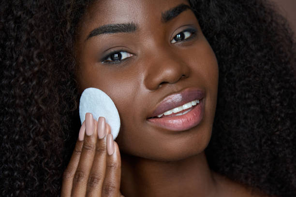 jeune femme noire tenant un coton en enlevant le maquillage du visage avec un démaquillant. - 5937 photos et images de collection