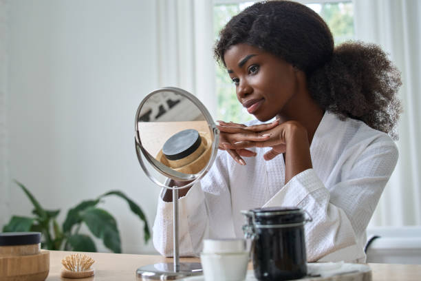 istock Happy pretty black young woman looking in mirror doing makeup. 1347464559