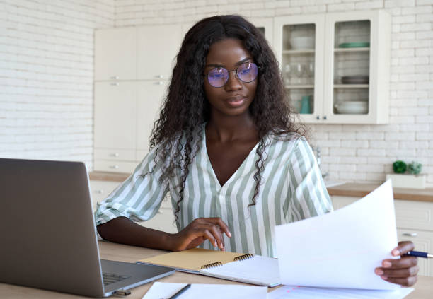 young intelligent mixed race businesswoman at desk with papers and laptop. - law student imagens e fotografias de stock