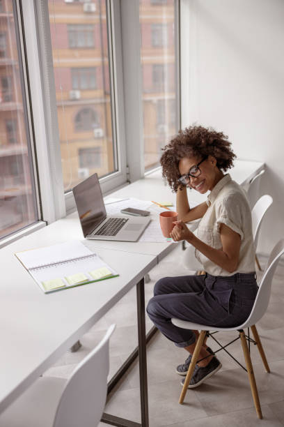 istock Pretty young lady resting while holding cup of drink in the office 1347470156