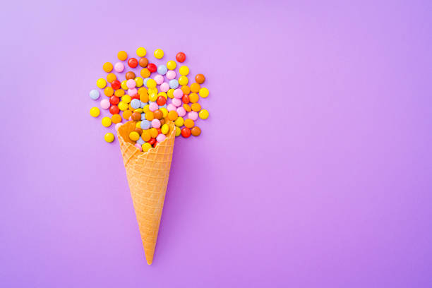 rożek do lodów z cukierkami na fioletowym tle - stick of hard candy candy vibrant color multi colored zdjęcia i obrazy z banku zdjęć