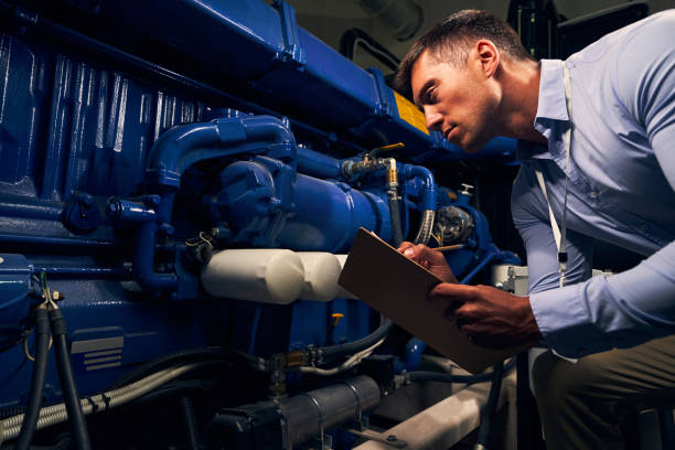 technicien de maintenance sérieux se penchant sur l’unité de production - générateur photos et images de collection