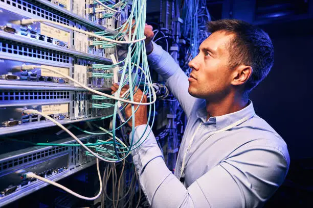 Photo of Skilled focused system administrator inspecting fiberl cabling