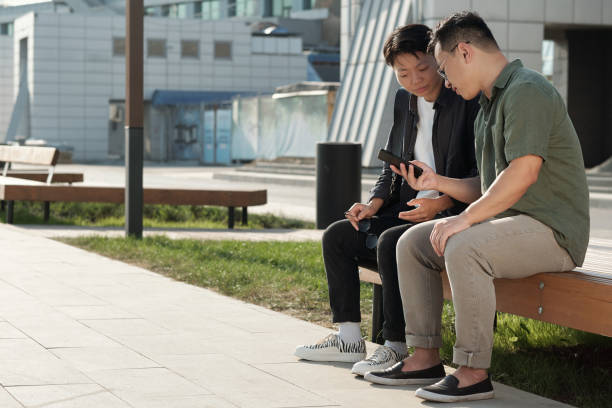 istock Two young Chinese businessmen looking at smartphone screen 1347478529