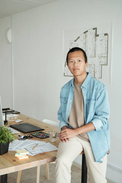 istock Contemporary young architect sitting on table against sketch on wall 1347478685