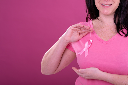Midsection of happy caucasian woman in pink tshirt with ribbon gesturing. breast cancer positive awareness campaign concept digitally generated video.