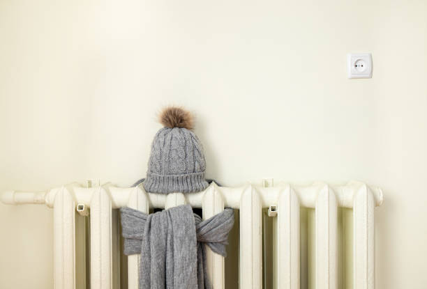 vintage heizkörper mit wollgestrickte wintermütze und schal. die strom- und gasrechnung steigt, europäisches energiekrisenkonzept. textraum im hintergrund, platz für text. - ölkrise stock-fotos und bilder