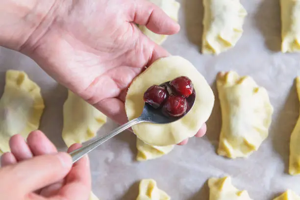 Making dumplings filled with sour cherry with sugar on a wooden cutting board