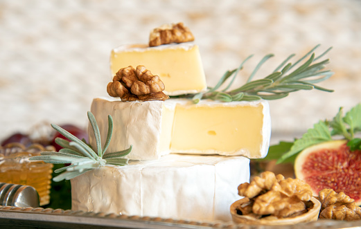 Cheese with white mold with herbs, nuts and fruits on a silver tray.