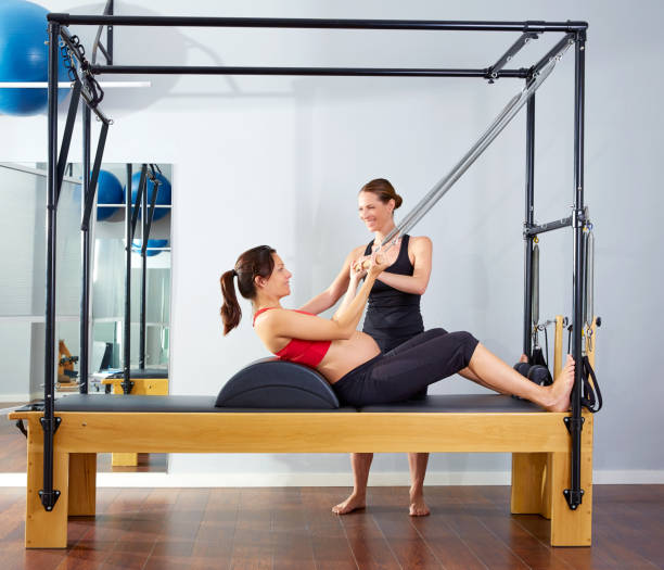 pregnant woman pilates reformer roll up exercise stock photo