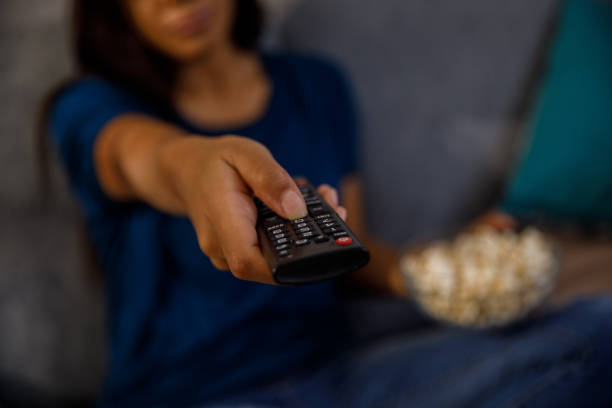 istock Woman pointing a remote control to her TV while playing a movie 1347484500