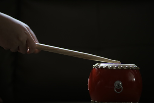 An Asian teenage girl is practicing drumming using dummy drum at home.