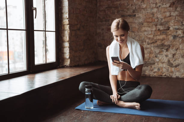 istock Fitness woman with towel sitting in gym while using phone 1347486685