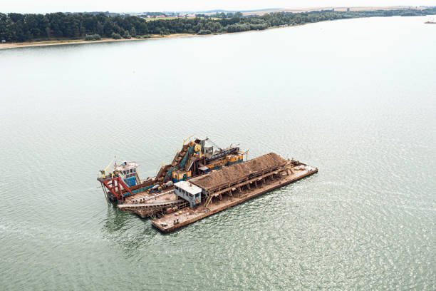 ein flussschiff extrahiert sand vom grund des flusses. reinigung des flusses von schlamm - industrial ship earth mover barge yellow stock-fotos und bilder