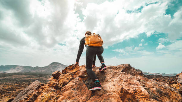 kobieta z plecakiem wędrująca po górach - turysta wspinający się na szczyt klifu - sport, sukces, przywództwo i koncepcja stylu życia - climbing hill zdjęcia i obrazy z banku zdjęć