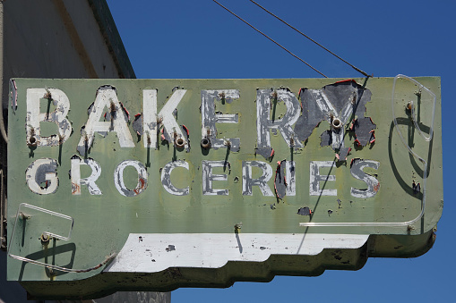 Old faded defunct and broken former neon sign BAKERY GROCERIES