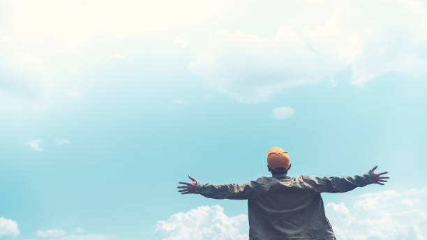 istock Copy space of man rising hands on blue sky white clouds abstract background. Freedom feel good and travel adventure concept. 1347492049